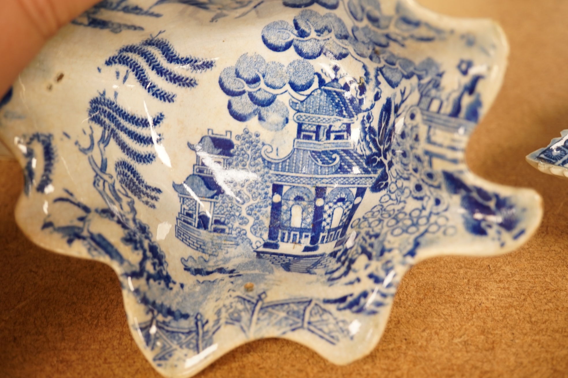 Two late 18th century Worcester or Caughley Cormorant fisherman pattern leaf pickle dishes and two early 19th century blue and white pottery leaf pickle dishes, largest 14.5cm long.